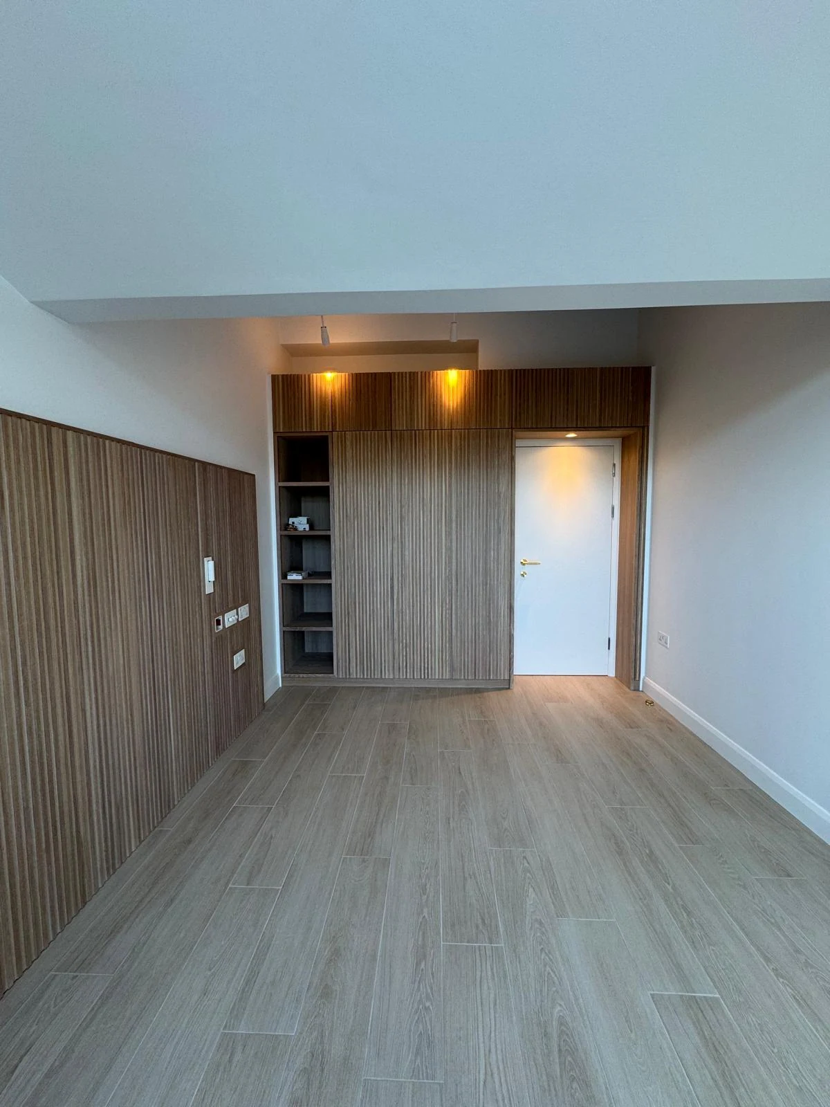 Wood-effect bespoke wall cabinetry with integrated lighting in a hallway