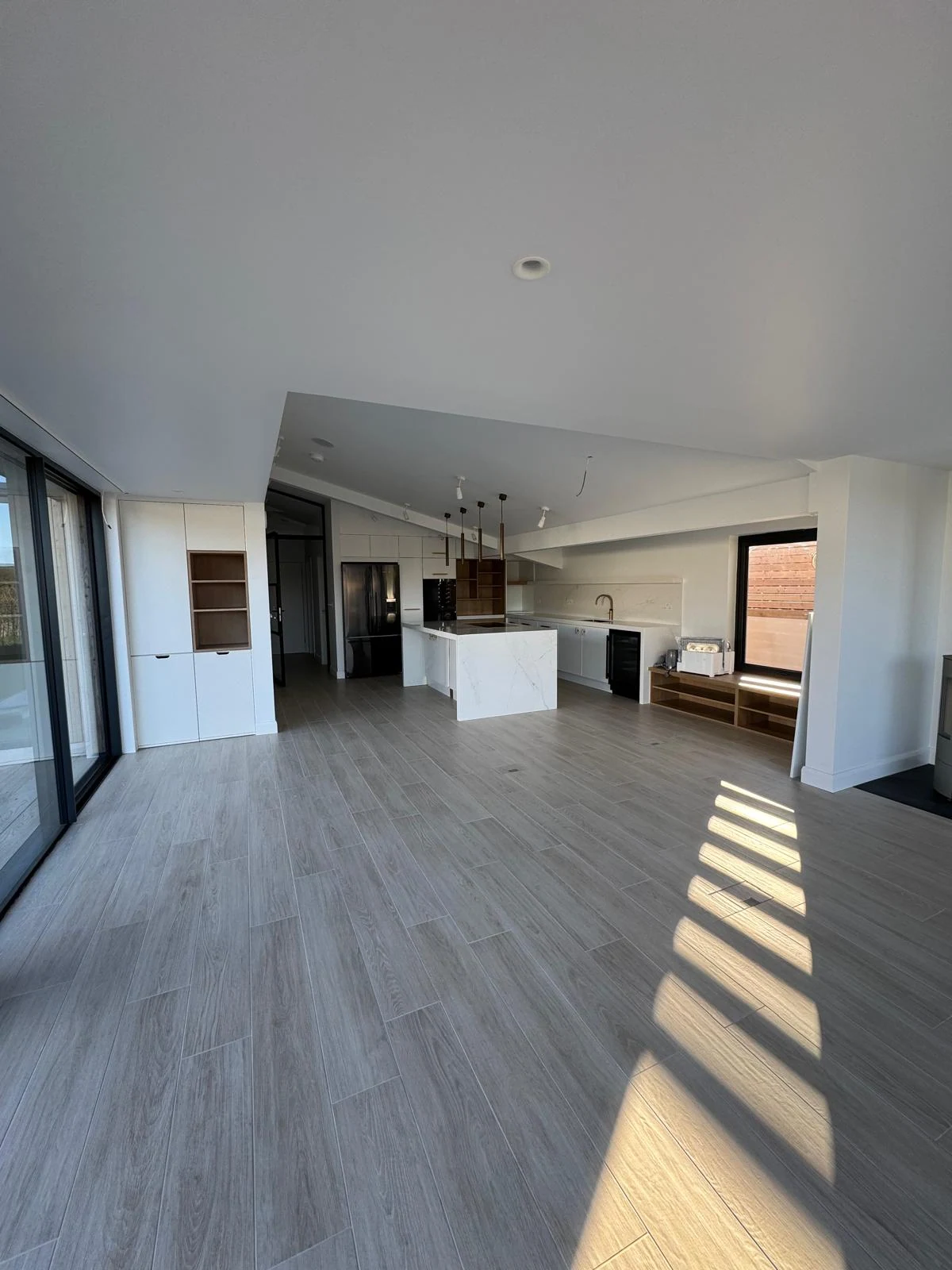 Open-plan kitchen with white island and oak-effect flooring