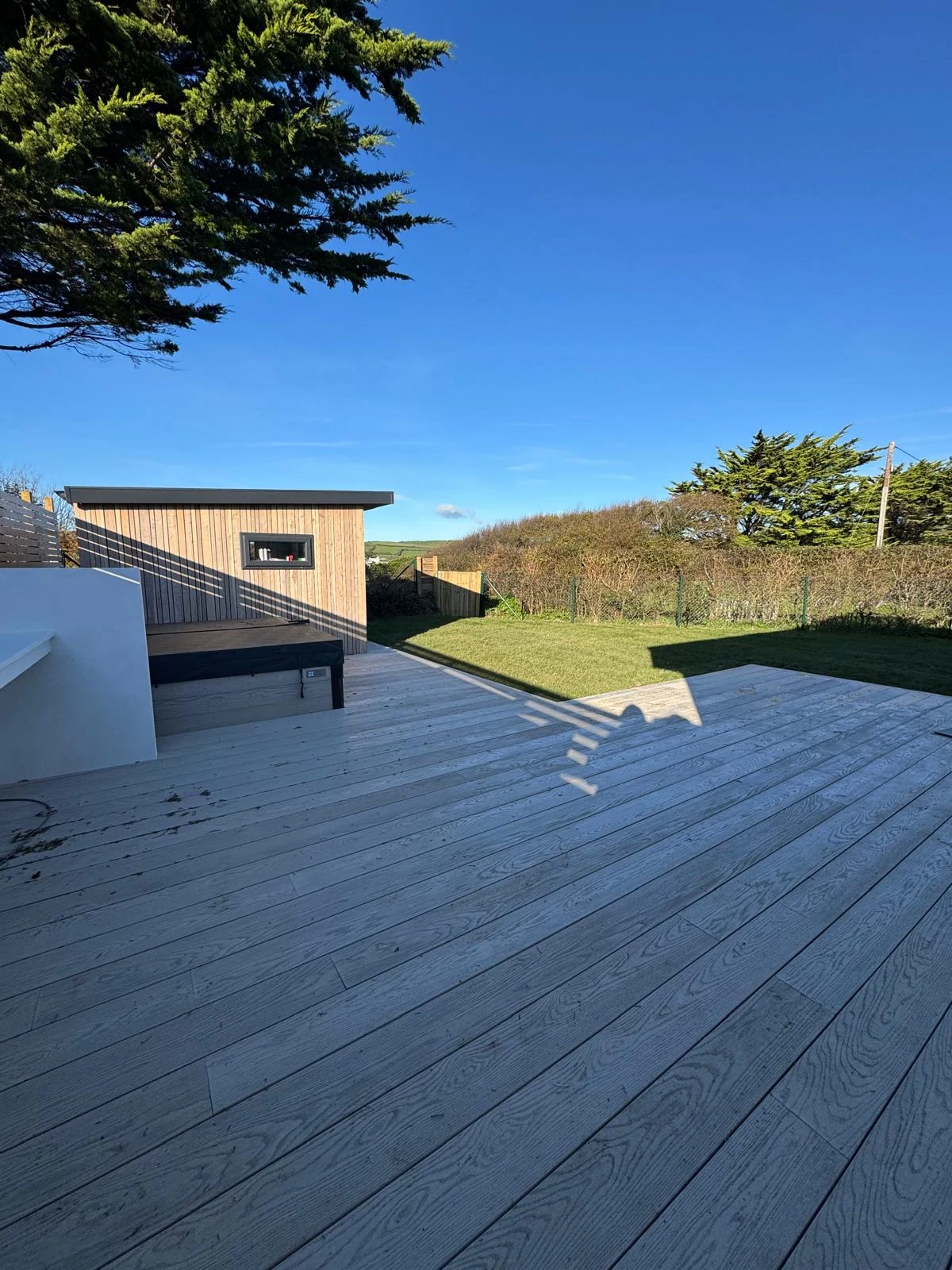 Garden office at the end of a composite deck in a coastal garden