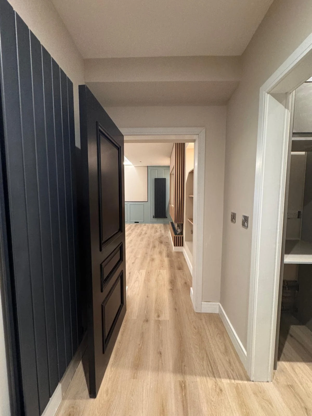 Black vertical panelling and hung internal door in a hallway