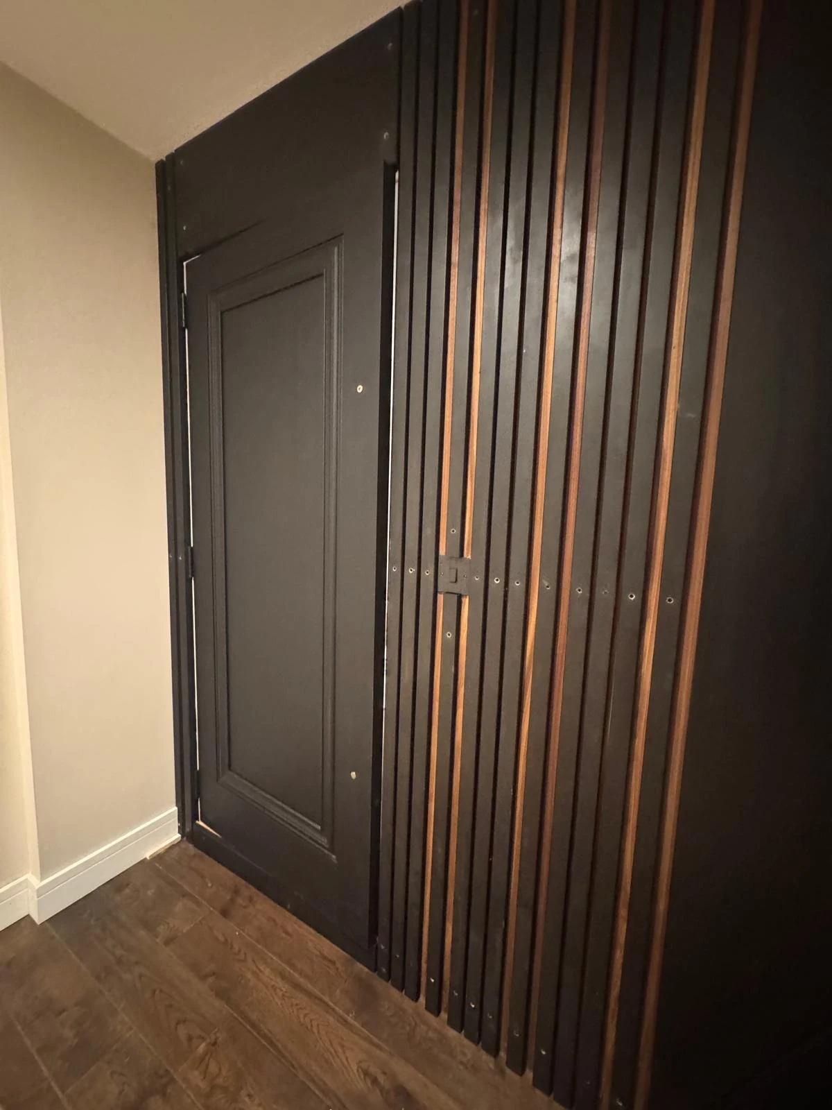 Dark vertical timber slatted wall panelling beside a door
