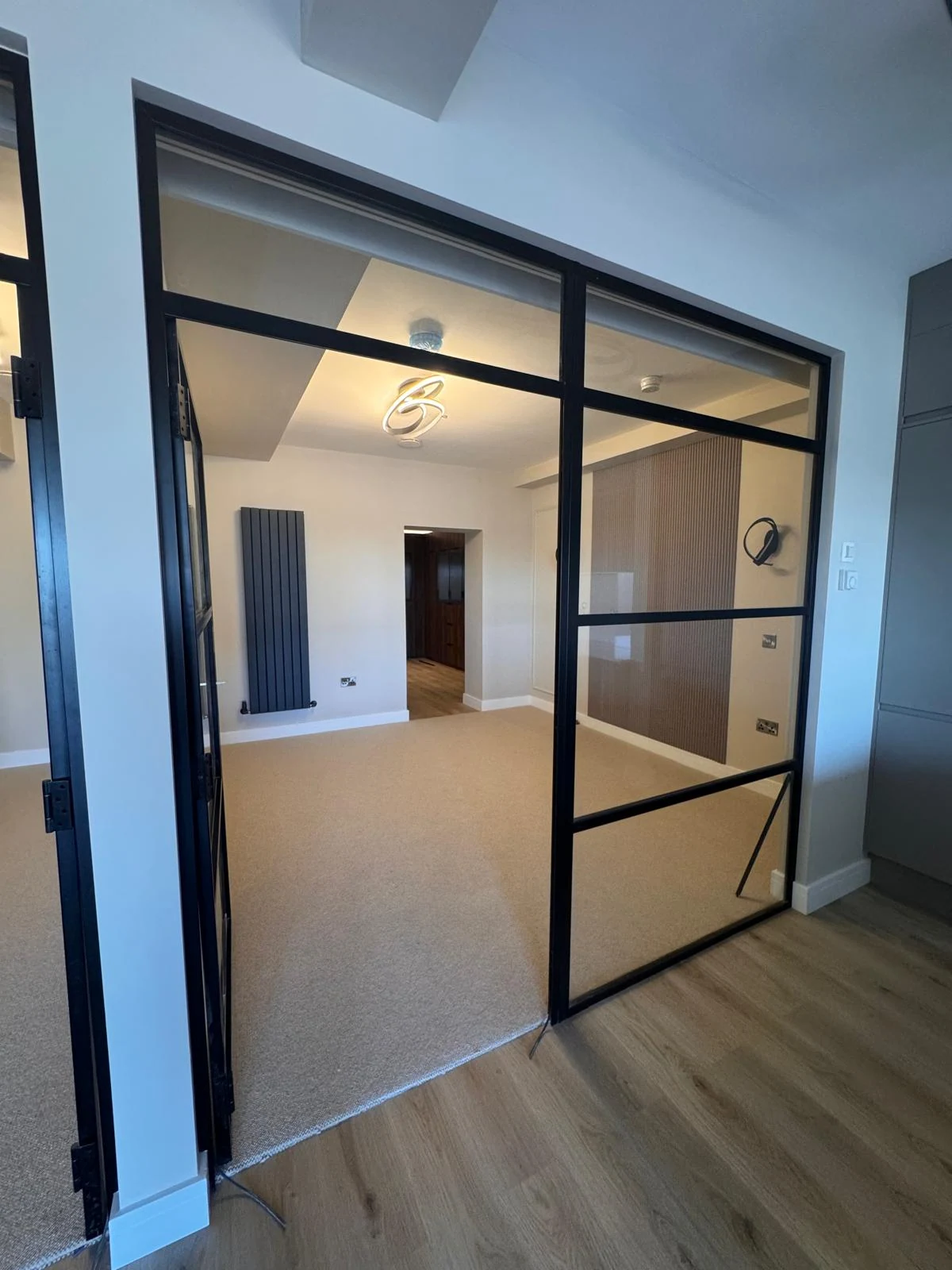 Crittall-style glazed partition wall separating a renovated room