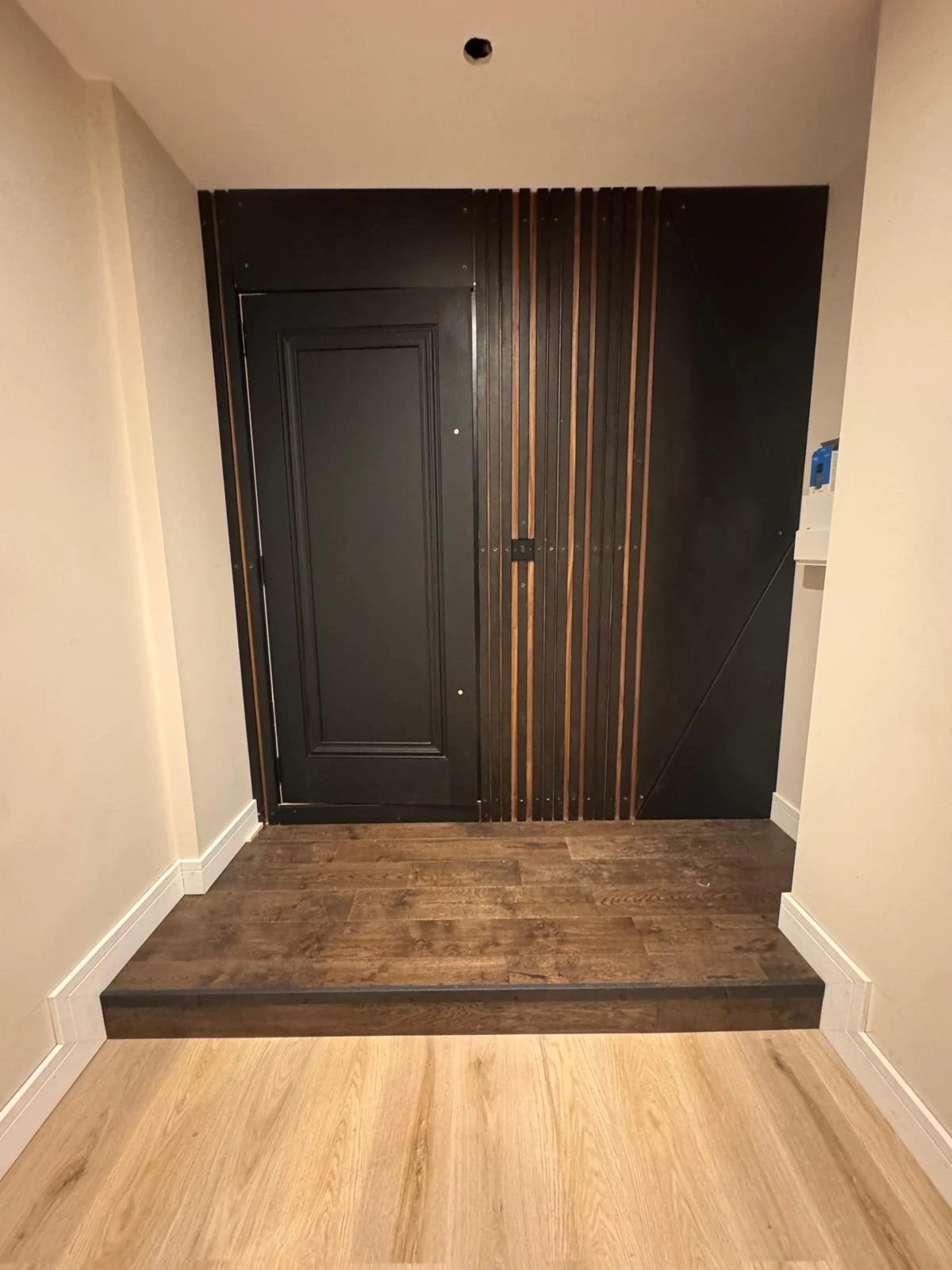 Black panelled door with oak bench seat joinery in a hallway