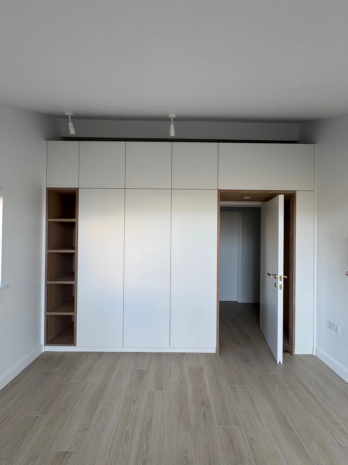 Fitted white bespoke wardrobes with open shelving in a bedroom