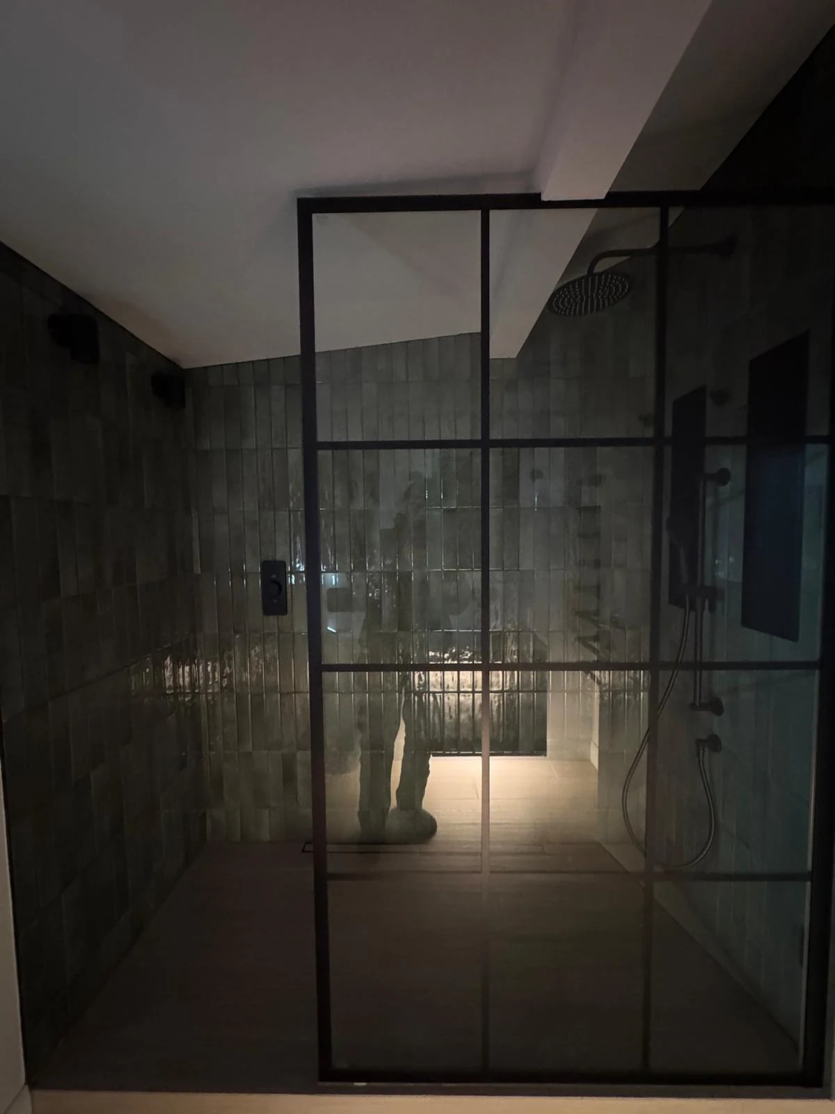 Glazed shower enclosure with dark tiles in a new build
