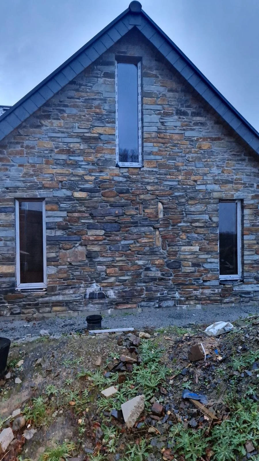 Stone-clad new build gable end under a blue sky