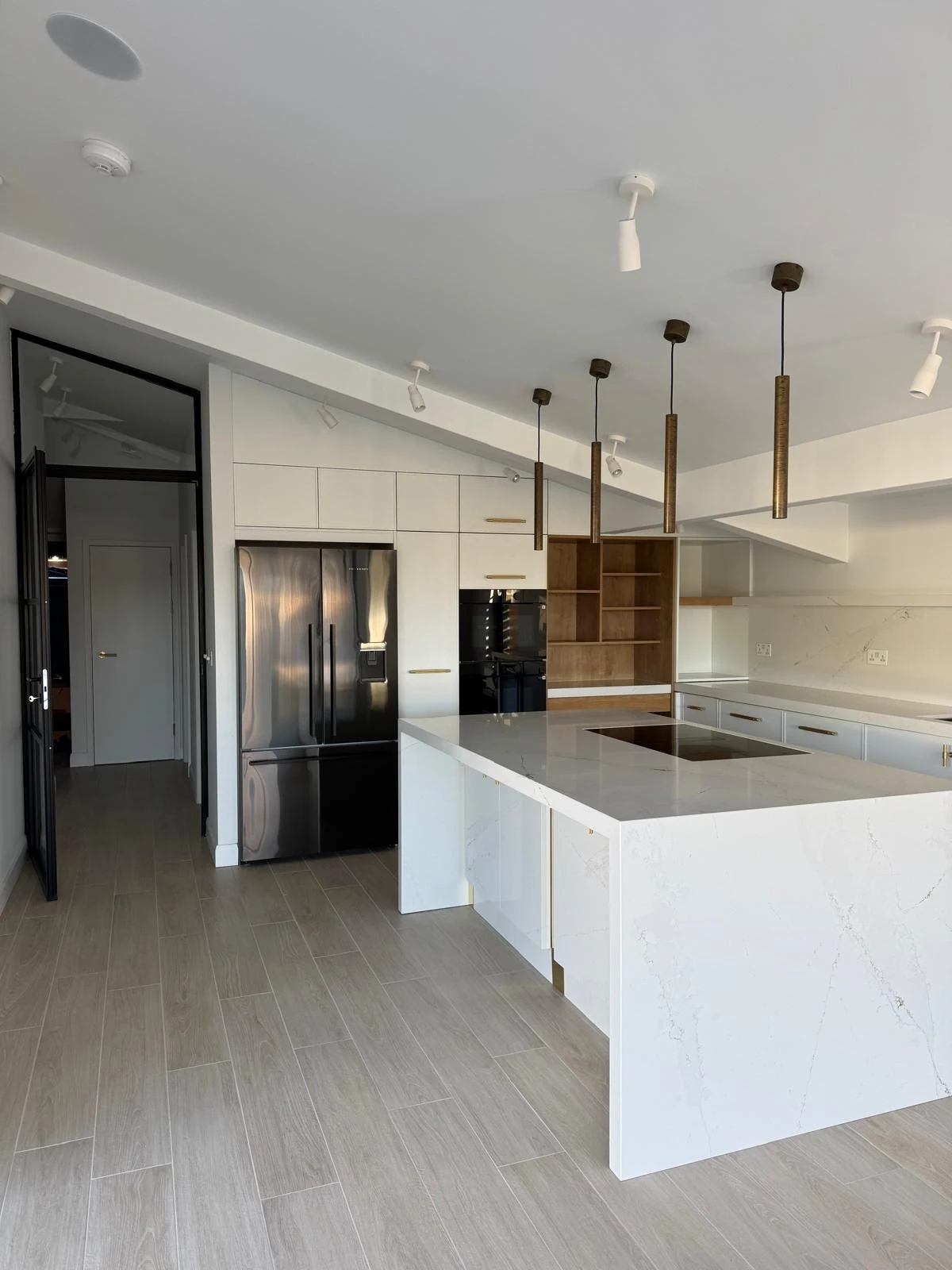 Modern kitchen with white island, pendant lights and black cabinetry