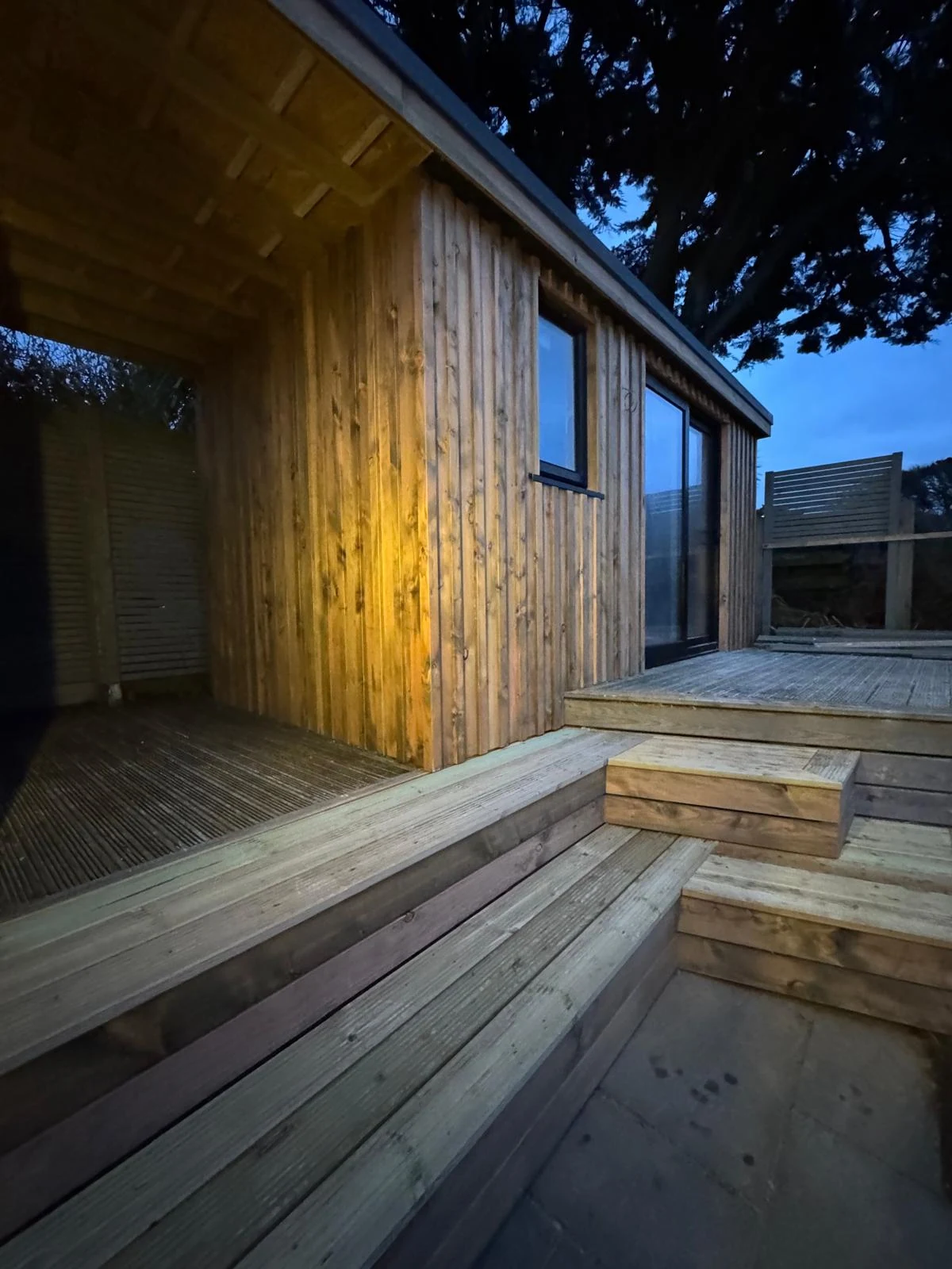Garden office with larch cladding, covered porch and timber deck steps