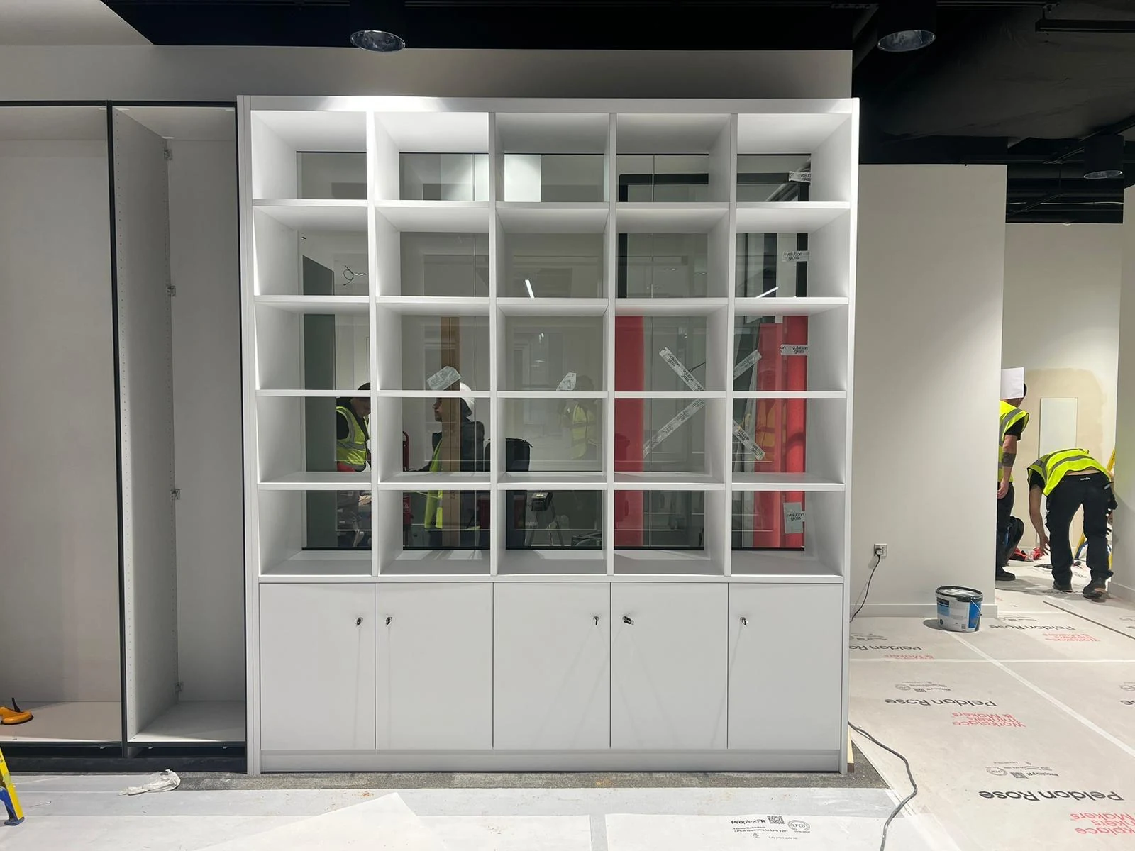 Bespoke white shelving and cupboard unit being installed in North Devon