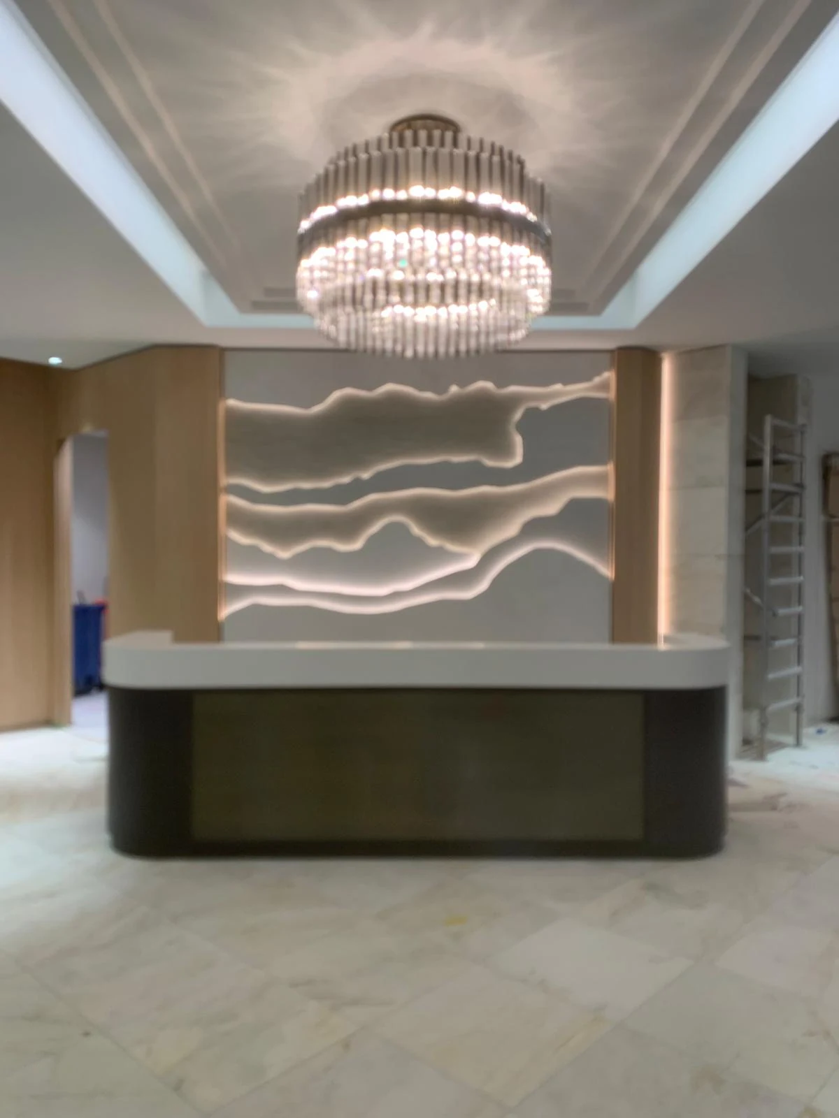 Curved reception desk with illuminated feature wall and chandelier