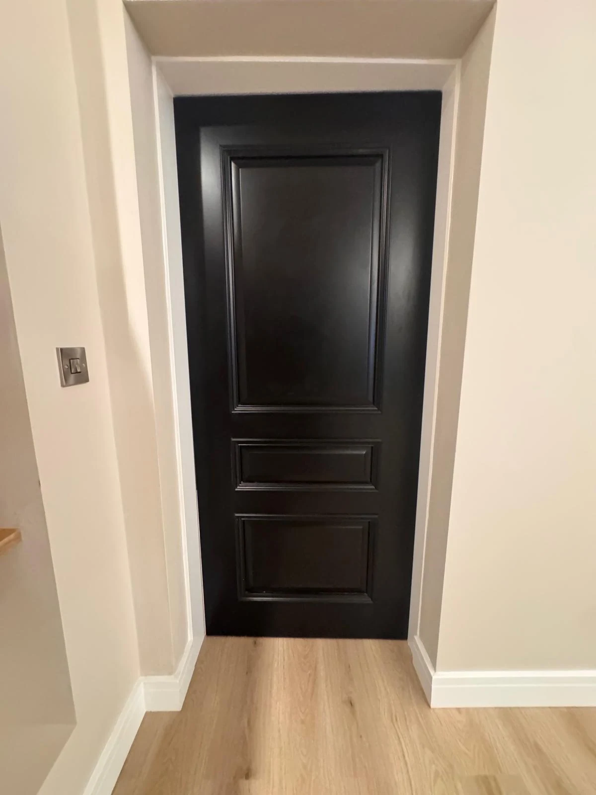 Black panelled internal door fitted with new architrave and skirting
