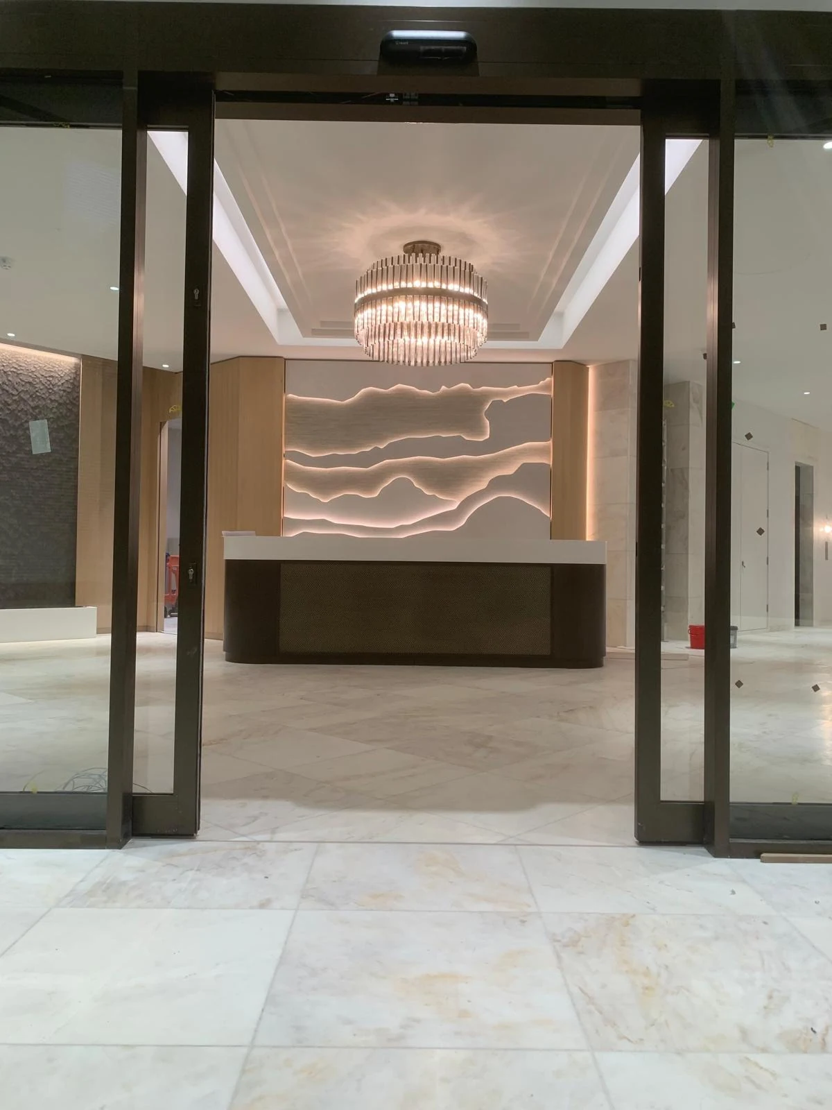 Glazed entrance framing a reception desk and illuminated wall