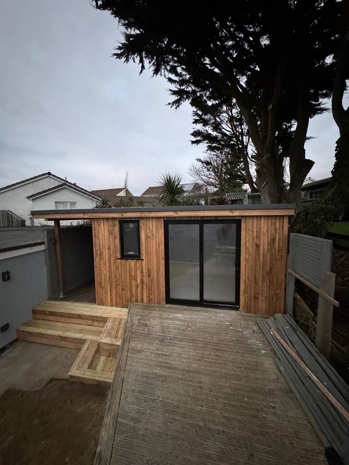 Garden office build with glazed doors beneath mature trees